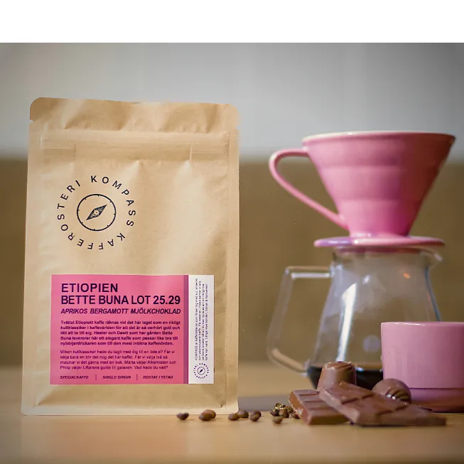 En påse Bette Buna från Kompass kafferosteri på ett bord med V60 och choklad